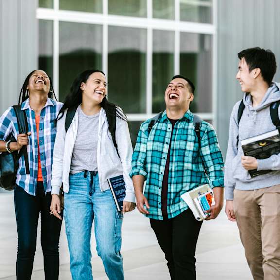 Four students walking together outside a building.