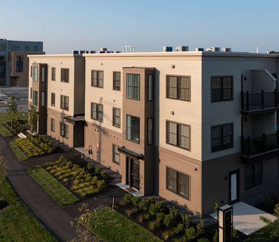 A modern apartment complex with a well-maintained lawn and landscaping.