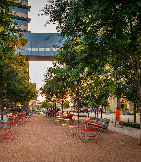 A park with benches and trees in front of a building.