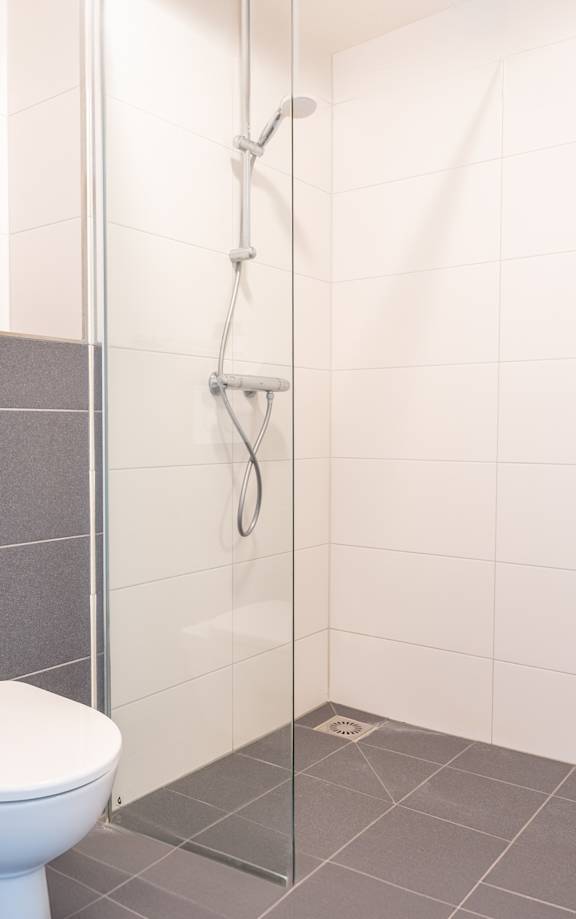 A white toilet is in a bathroom with a white sink and a glass shower door.