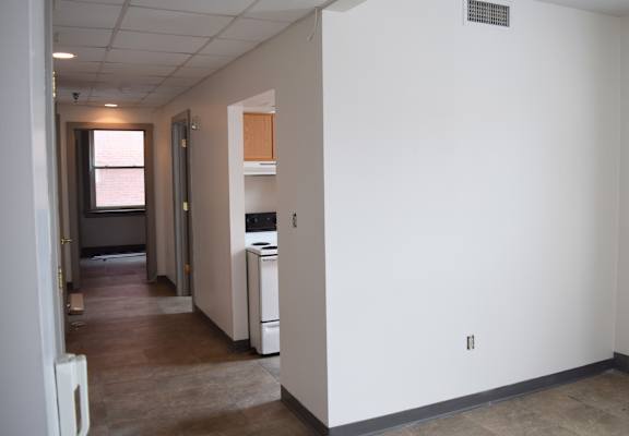 A kitchen area with a refrigerator, sink, and cabinets.