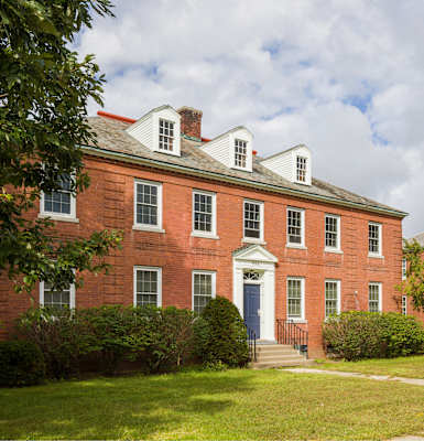 A red brick building with a white door and windows.