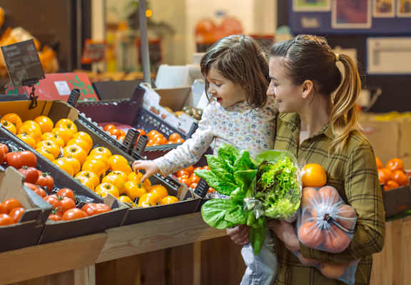 a mother and daughter selecting vegetables at a grocery store
