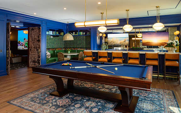 A pool table is in the middle of a room with a blue wall.