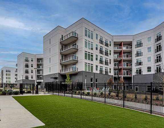 new apartment buildings with a green lawn and a bench at Centro at Pine Nash in Wilson, North Carolina