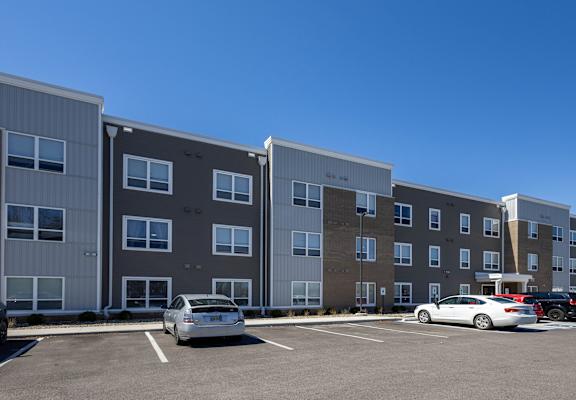 A parking lot with cars and apartment buildings.