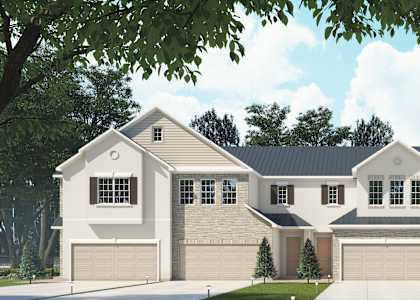 A large, two-story house with a garage is surrounded by trees.