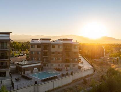 A sunset view of apartment buildings with a pool in the foreground.