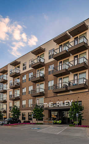 The Riley apartment complex has a parking lot in front.
