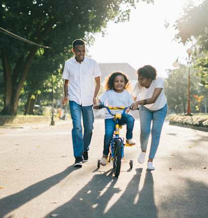 A family of three is walking together in a park with a child on a bicycle.at Union at 16th, Indianapolis, 46222