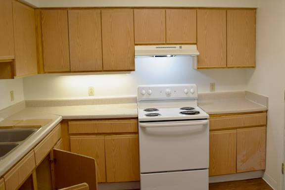 A kitchen with a white stove and wooden cabinets.