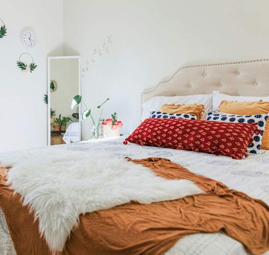 a bedroom with a bed with red pillows and a white blanket