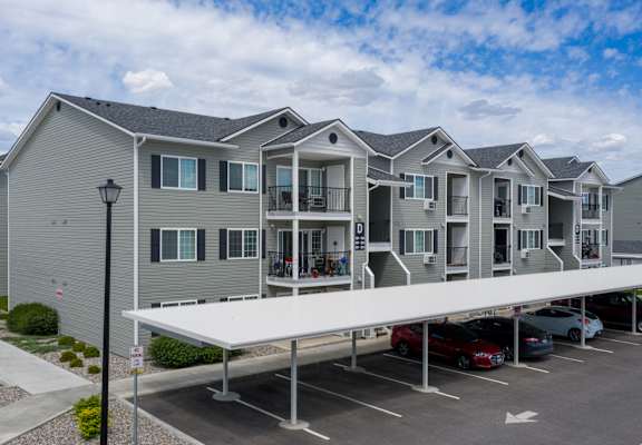 a row of apartment buildings with cars parked in a parking lot