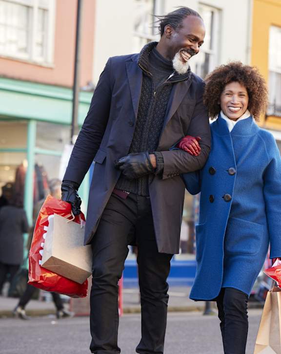 A man and a woman are walking down the street carrying shopping bags.