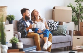 Couple sitting on the couch surrounded by moving boxes