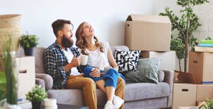 Couple sitting on the couch surrounded by moving boxes
