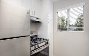 A white fridge and stove in a kitchen with a window.