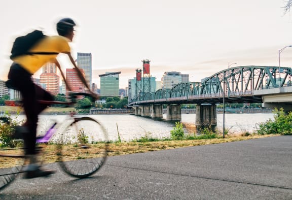 a man riding a bike on a path next to a bridge