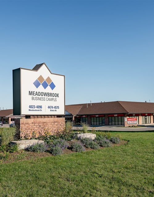a picture of the meadowbrook business center sign in front of the building
