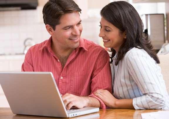 a man and woman looking at a laptop computer