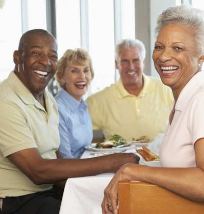 A group of people are sitting around a table smiling.
