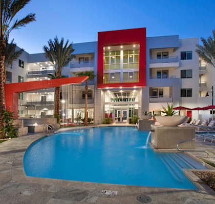 a swimming pool in front of an apartment building at night