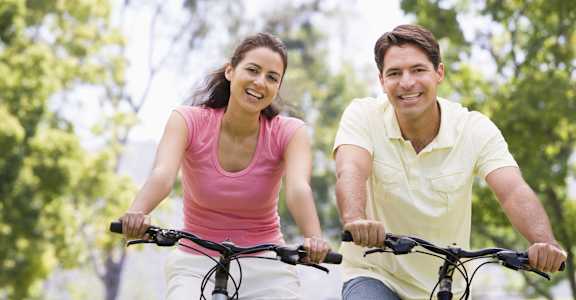 a man and a woman riding bikes in a park