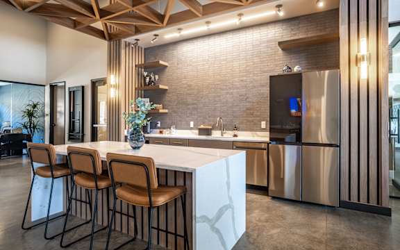 A modern kitchen with a bar area and chairs.