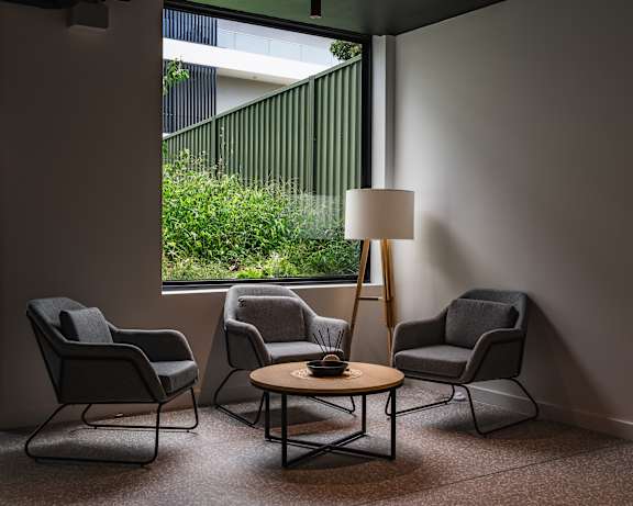 a living room with three chairs and a table and a floor lamp