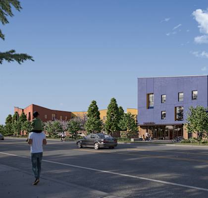 A man is walking on the street in front of a purple building.