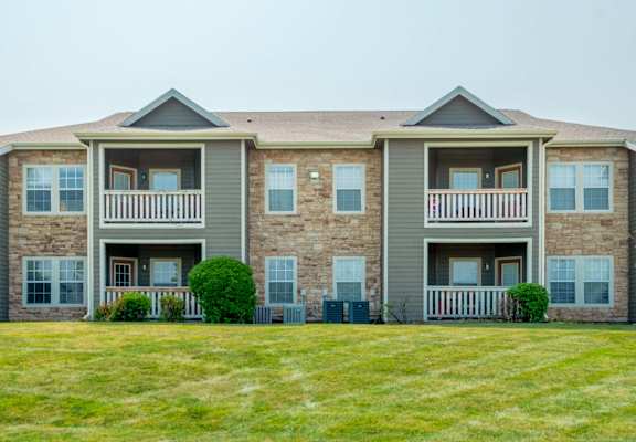 an apartment building with a lawn and a sidewalk in front of it