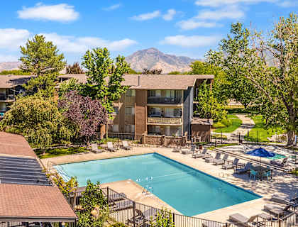 A large swimming pool is surrounded by a fence and chairs.