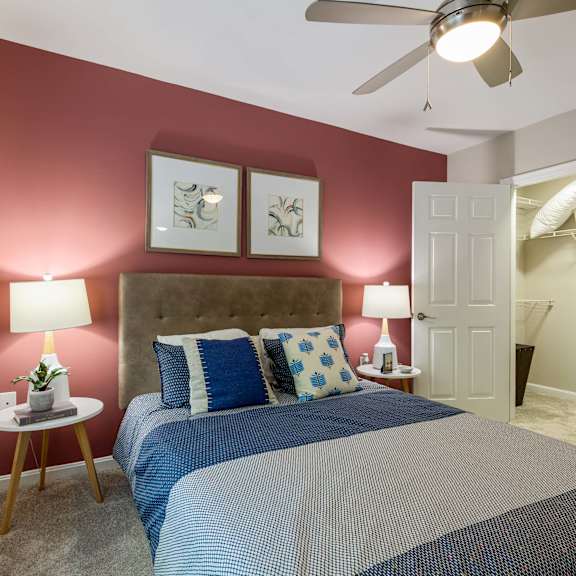 A bedroom with a bed, two lamps, and a ceiling fan.