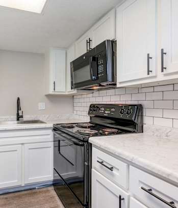 a kitchen with white cabinets and a black stove and microwave