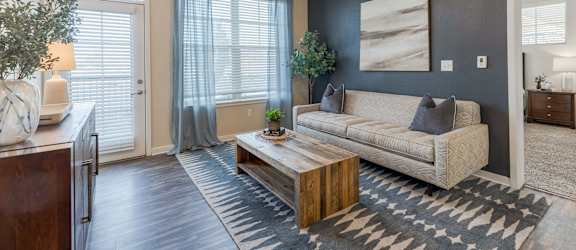 A living room with a beige couch, a wooden coffee table, and a ceiling fan.