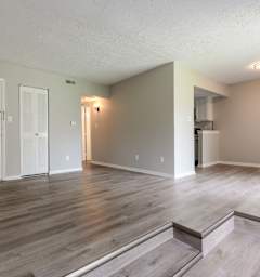 the living room and kitchen of an empty apartment with wood floors