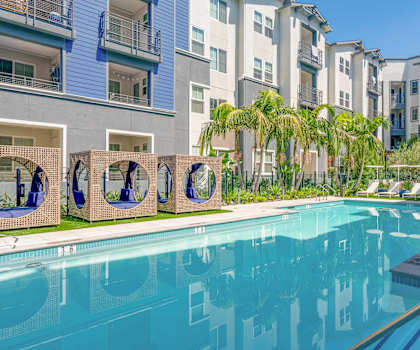 A swimming pool in front of a building with a blue sky in the background.