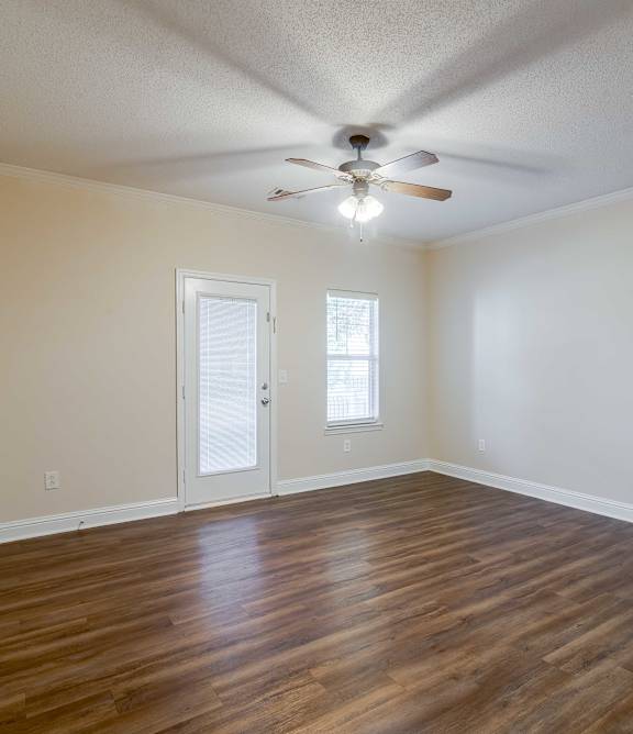 A living room with a yellow couch, a coffee table, and a ceiling fan at Bedford Parke Apartments, GA, 31088