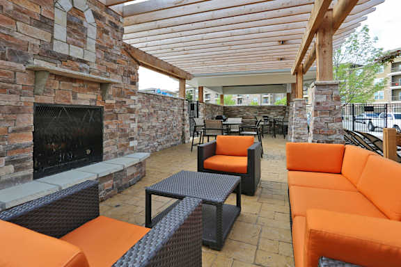 Outdoor lounge with stone fireplace and vibrant orange seating  at Residences at Prairiefire Apartment Homes, Overland Park, 66223