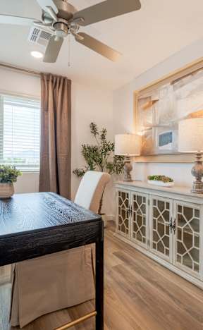 A room with a table, chairs, and a ceiling fan.