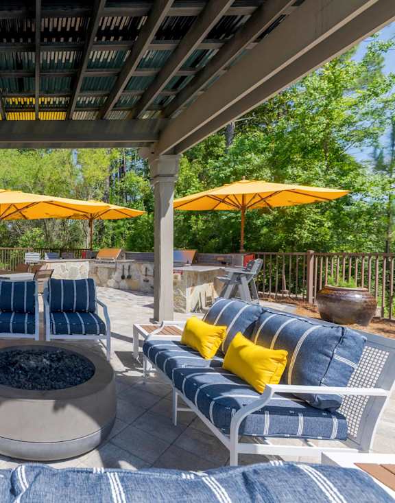 A patio with blue and yellow cushions and two yellow umbrellas.