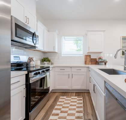 A kitchen with white cabinets and a checkered floor.