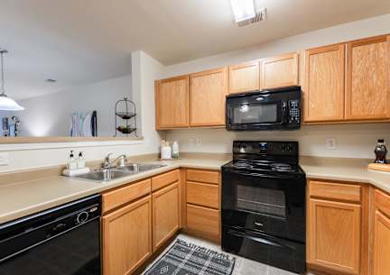 A kitchen with black appliances and wooden cabinets.