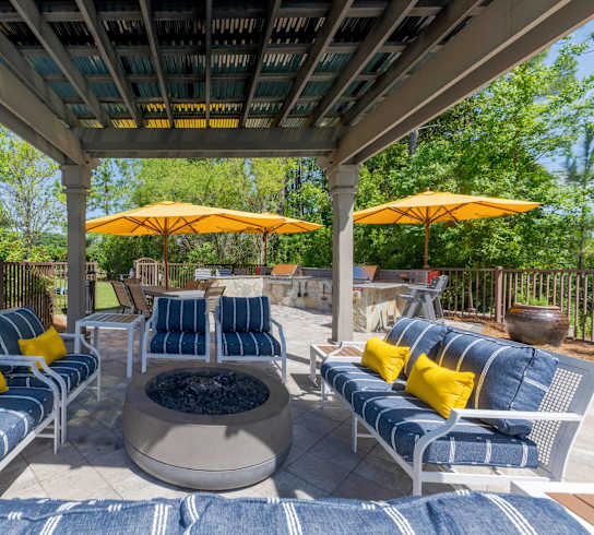 A patio with blue and yellow cushions and two yellow umbrellas.