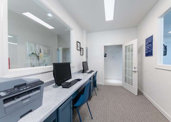 A white room with a desk and two computers on it.