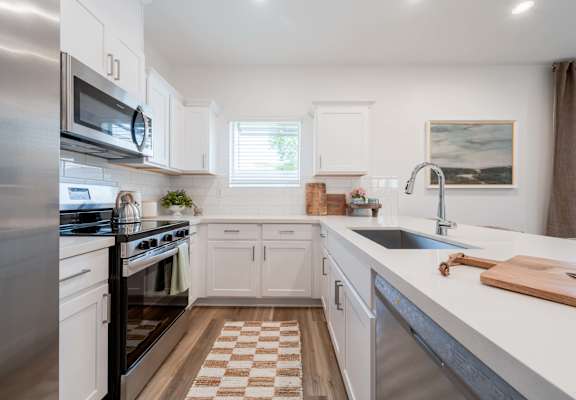 A kitchen with white cabinets and a checkered floor.