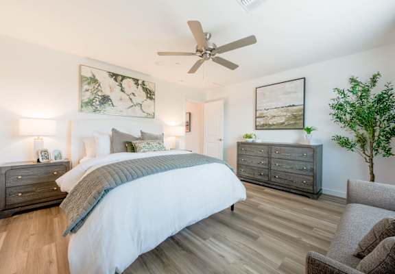 A bedroom with a large bed, a dresser, and a ceiling fan.
