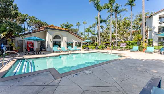 A large outdoor swimming pool surrounded by a brick patio and lounge chairs.