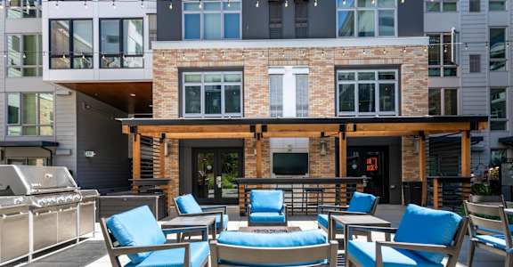 A patio with blue chairs and a table with a blue cushion.
