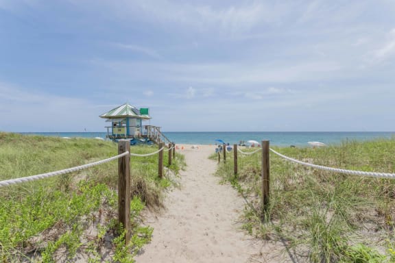 a path to the beach with a lifeguard tower in the background